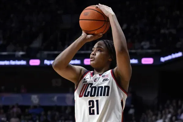 سارة سترونغ، لاعبة كرة سلة من فريق UConn، تستعد لإطلاق تسديدة أثناء مباراة، مع التركيز على مهاراتها في التهديف والتمرير.