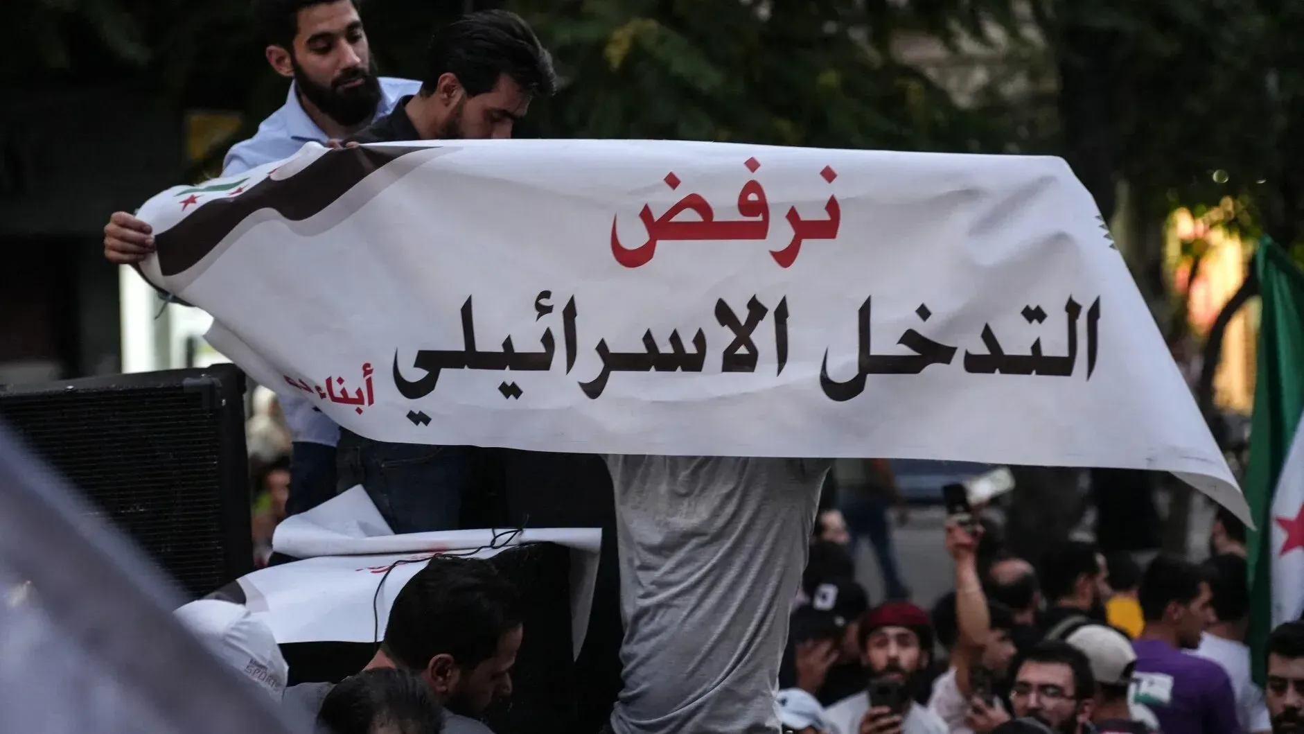 محتجون يحملون لافتة مكتوب عليها "نرفض التدخل الإسرائيلي" في ساحة الأمويين بدمشق، تعبيرًا عن رفضهم للهجمات الإسرائيلية على سوريا.