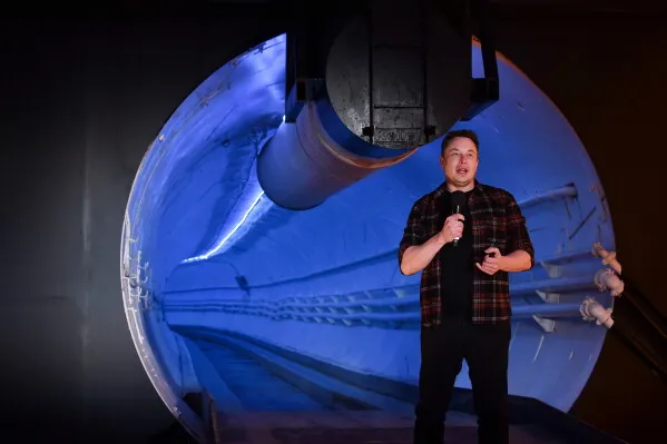 إيلون ماسك يتحدث في نفق تحت الأرض تابع لشركته The Boring Company، مع خلفية مضيئة تعكس الابتكارات في النقل الحضري.
