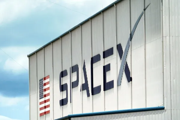 شعار شركة SpaceX على جدار المنشأة، مع العلم الأمريكي، يمثل الابتكار في صناعة الفضاء وتكنولوجيا الفضاء.