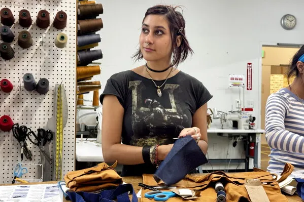 شابّة تتعلم مهارات الخياطة اليدوية ضمن برنامج Levi's لتعزيز الاستدامة وترميم الملابس لجيل Z في ورشة خياطة.