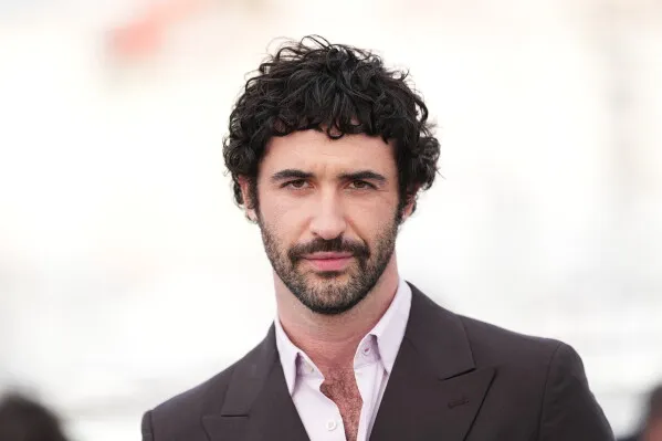 شخصية شاب ذو لحية وشعر مجعد، يرتدي بدلة أنيقة، يبدو واثقًا في حدث سينمائي، مما يعكس التحول الجديد في صناعة السينما.