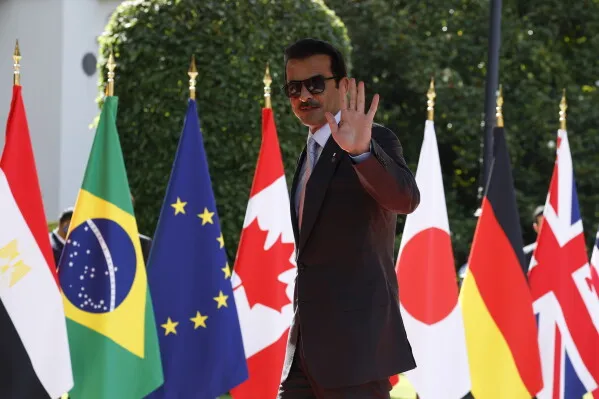 الرئيس الأوكراني فولوديمير زيلينسكي يلوح بيده أثناء وصوله إلى قمة مجموعة السبع في إيفيان-ليه-بان، محاطًا بأعلام الدول المشاركة.