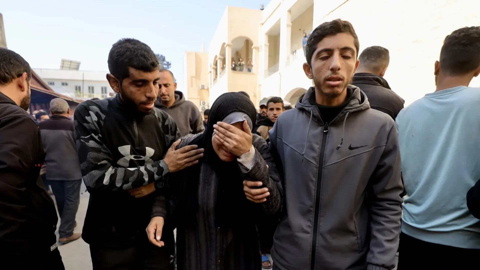 امرأة تبكي وسط مجموعة من الناس في غزة، تعبر عن الحزن بعد فقدان عائلتها في الهجمات الإسرائيلية الأخيرة.