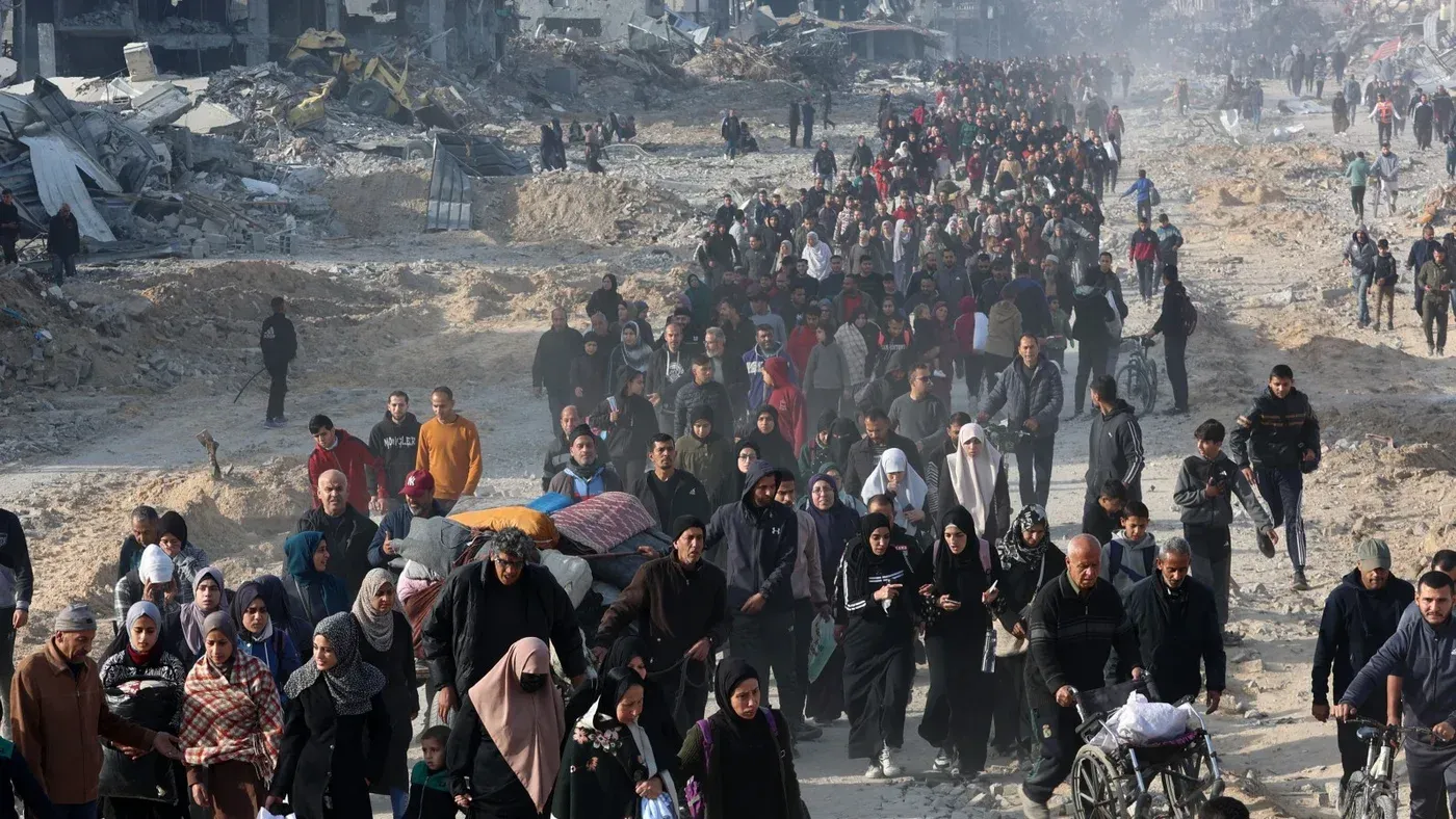 مئات من الفلسطينيين يسيرون عبر أنقاض مدينة غزة، يحملون الأمتعة وسط سحب من الغبار، معبرين عن معاناتهم في ظل الحرب.