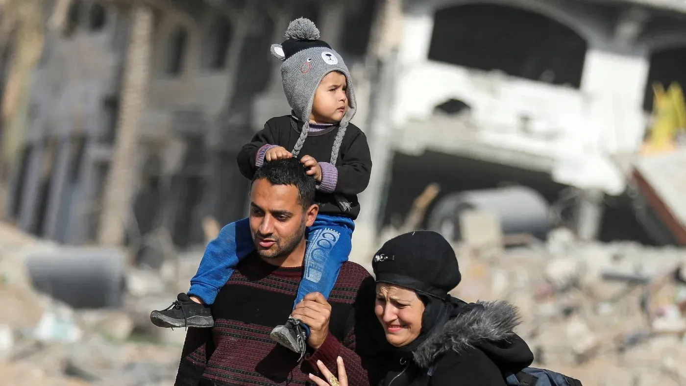 أسرة فلسطينية تمر عبر أنقاض منزل مدمَّر في خان يونس، تعبير عن الألم والأمل في العودة وسط آثار الحرب المدمِّرة.