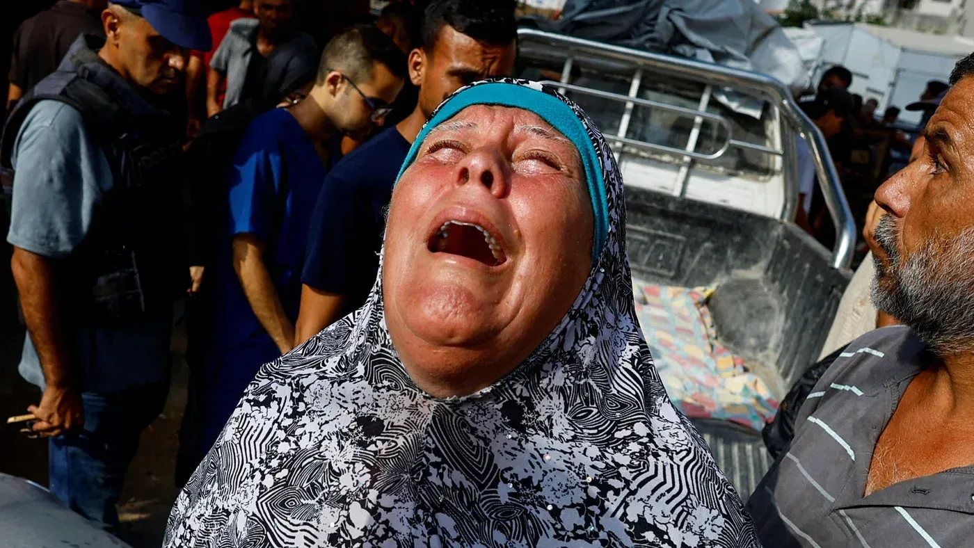 امرأة فلسطينية تبكي بحرقة في حي الزيتون بغزة، محاطة بالناس، تعبر عن ألم الفقد والدمار الناتج عن القصف المستمر.