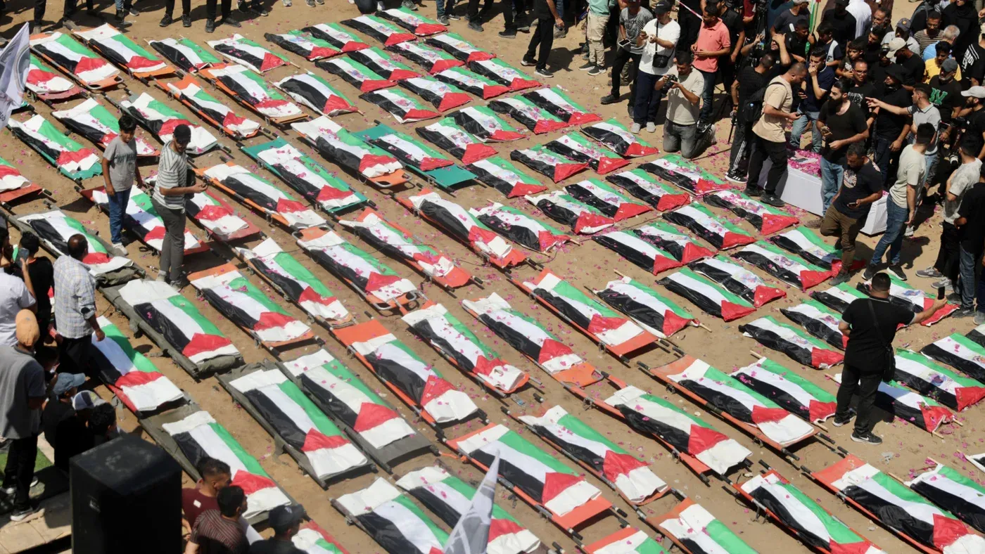 جثامين 112 فلسطينياً من عائلتي أبو شريعة والحسينة مغطاة بالأعلام الفلسطينية في جنازة جماعية بمدينة غزة بعد غارات إسرائيلية.