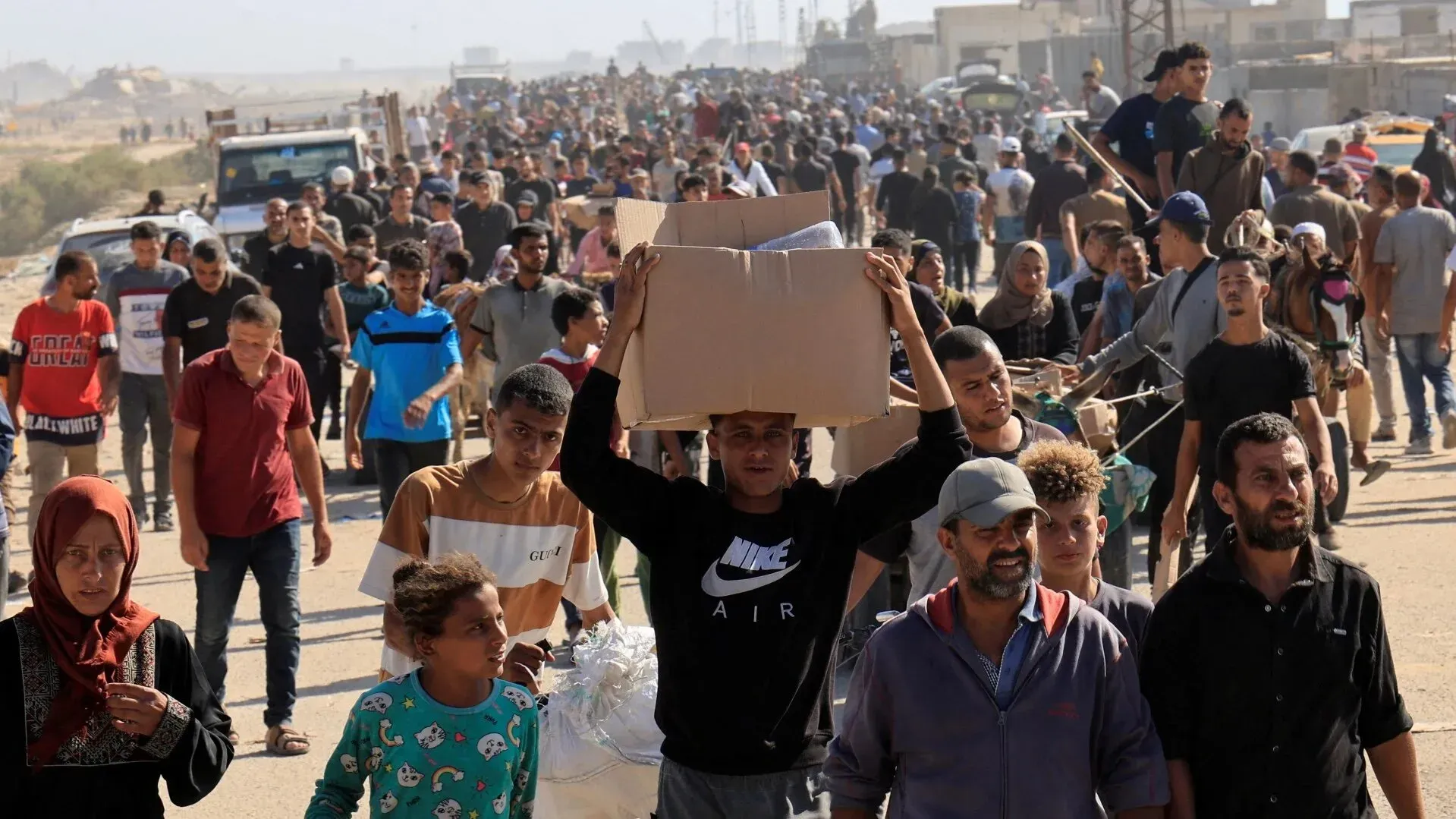 حشود من الفلسطينيين في غزة ينتظرون المساعدات الإنسانية، وسط ظروف قاسية، بينما تتصاعد الأوضاع الإنسانية.