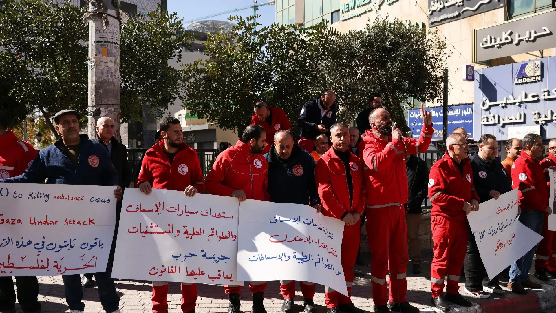 تجمع أفراد من الهلال الأحمر الفلسطيني في مظاهرة، حاملين لافتات تعبر عن استنكارهم لاستهداف طواقم الإسعاف في غزة.