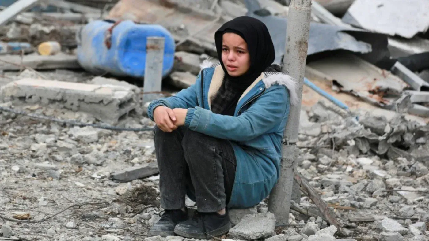 طفلة فلسطينية تجلس على أنقاض مبنى مدمّر، تعبر عن الحزن والقلق في ظل الأوضاع الصعبة في غزة.