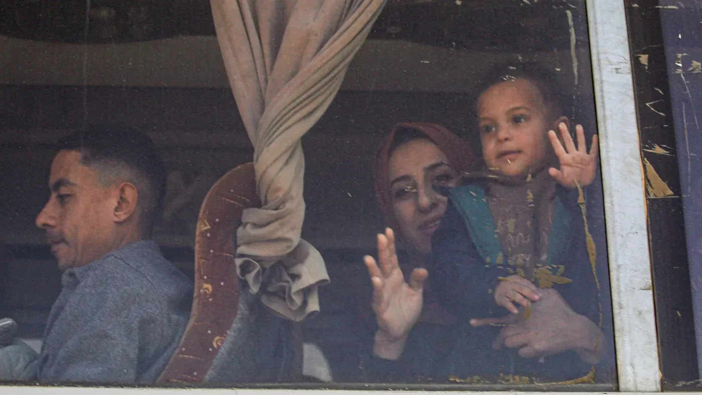 عائلة فلسطينية تنتظر عند معبر رفح، حيث يُسمح بعبور 50 شخصًا يوميًا من مصر إلى غزة، وسط ظروف صعبة.