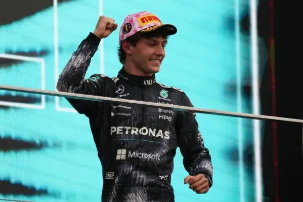 جورج راسل يحتفل بفوزه، مرتديًا زي فريق مرسيدس، مع تعبير عن السعادة والثقة، في سياق منافسات الفورمولا 1.