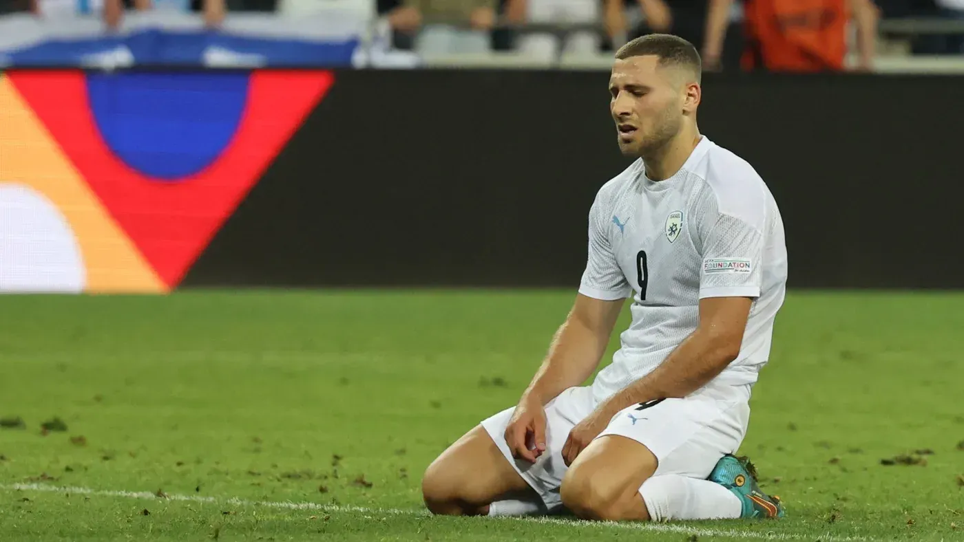 لاعب كرة القدم شون فايسمان يجلس على الأرض بملابس رياضية، معبرًا عن الإحباط بعد مباراة، في سياق الجدل حول تصريحاته المثيرة للجدل.