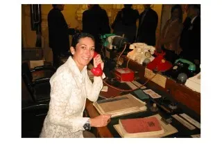 غيسلين ماكسويل تجلس على مكتب، تتحدث عبر هاتف أحمر، محاطة بأشخاص آخرين، في سياق التحقيقات حول علاقاتها بجيفري إبشتاين.