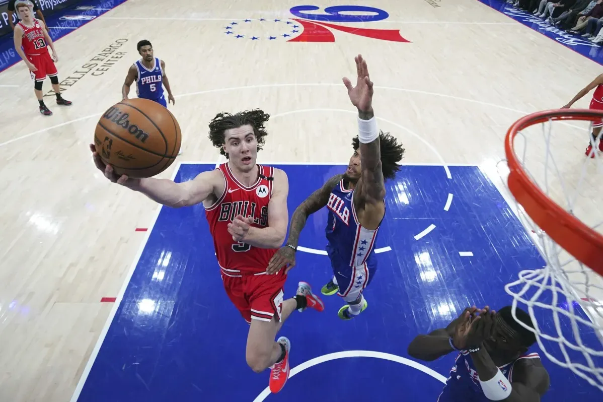 لاعب شيكاغو بولز يسجل سلة خلال مباراة ضد فيلادلفيا 76ers، مع وجود لاعبين آخرين في الخلفية.