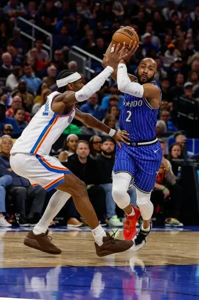 لاعب من فريق أورلاندو ماجيك يحاول تسديد الكرة بينما يتصدى له لاعب من أوكلاهوما سيتي ثاندر خلال مباراة مثيرة.