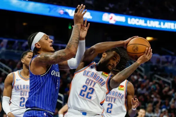 مواجهة مثيرة بين لاعبي أوكلاهوما سيتي ثاندر وأورلاندو ماجيك، حيث يحاول لاعب ثاندر الاستحواذ على الكرة وسط ضغط من لاعب ماجيك.