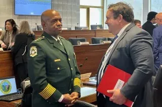 اجتماع لمشرعي ولاية كارولينا الشمالية حول مكافحة الجريمة، يظهر ضابط شرطة يتحدث مع مسؤول، وسط مناقشات بشأن قضايا العدالة الجنائية.