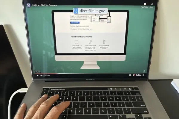 واجهة موقع "التقديم المباشر" للضرائب تظهر على شاشة كمبيوتر محمول، مع يد تكتب على لوحة المفاتيح.