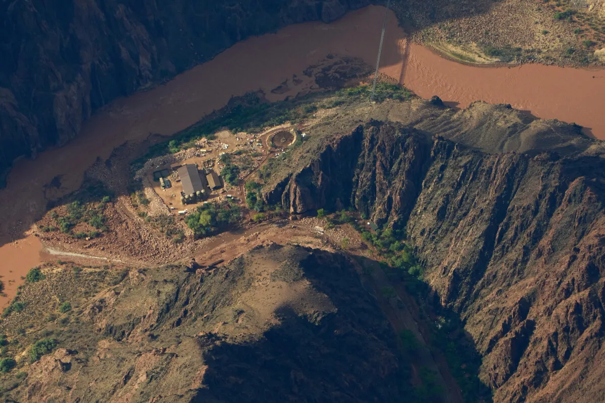 منظر جوي لوادي Grand Canyon يظهر نهرًا طينيًا وموقعًا متضررًا بفعل فيضان أثر على خط مياه Transcanyon القديم والهش.