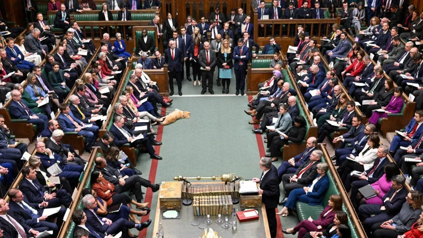 جلسة البرلمان البريطاني مكتظة بالنواب، مع وجود زعيم حزب العمال كير ستارمر يتحدث من المنصة، بينما يظهر كلب مستلقي على الأرض.