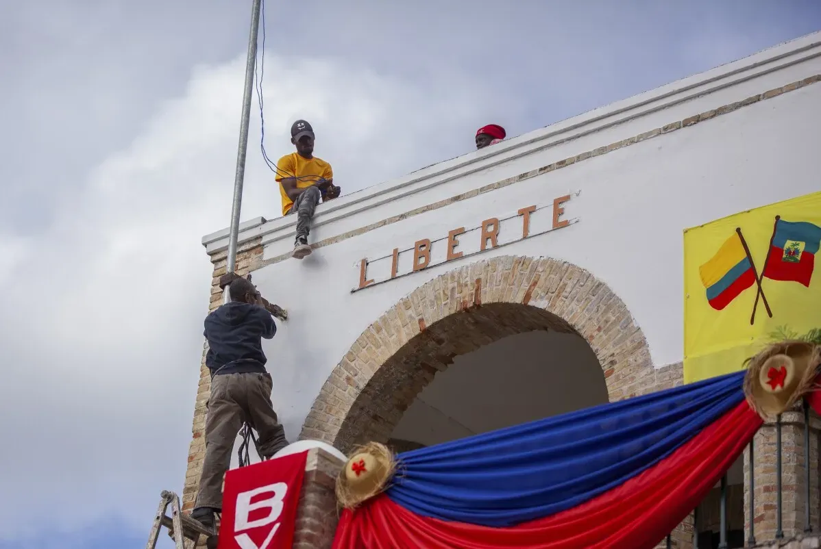 عمال يقومون بتركيب علامة "LIBERTE" على مبنى في جاكميل، هايتي، تزامناً مع التحسينات في البنية التحتية بعد زيارة الرئيس الكولومبي.