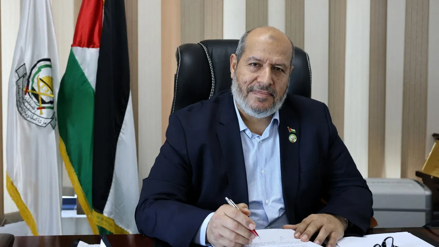 خليل الحيّة قائد حركة حماس الجديد يجلس في مكتبه مع أعلام الحركة وفلسطين خلفه، يعكس دوره القيادي والتفاوضي.
