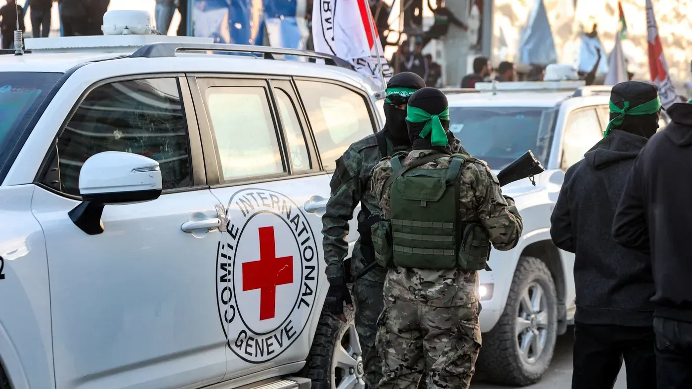 مقاتلون من حماس يتحدثون بجانب سيارة تابعة للجنة الدولية للصليب الأحمر، في سياق جهود لتأمين المساعدات الإنسانية لغزة.
