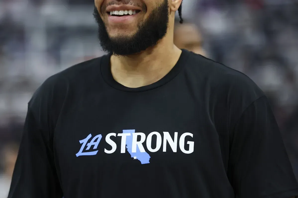 لاعب يرتدي قميصًا أسود مكتوب عليه \"LA STRONG\" مع خريطة صغيرة لكاليفورنيا، يعكس دعم لوس أنجلوس بعد حرائق الغابات.