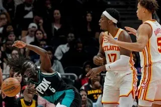 لاعب من فريق بورتلاند تريل بليزرز يسقط أثناء المنافسة مع لاعبي أتلانتا هوكس، مما يعكس حماس المباراة وأداء الفرق.