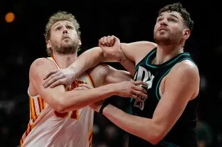 مباراة كرة سلة بين لاعبي أتلانتا هوكس وبورتلاند تريل بليزرز، حيث يظهر التنافس بين اللاعبين خلال اللعب.