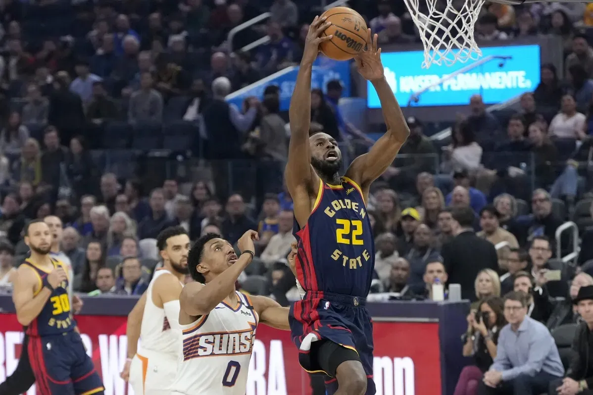 لاعب غولدن ستايت أندرو ويجينز يسجل نقطة خلال مباراة، بينما يحاول لاعب من فريق صنز الدفاع عنه.