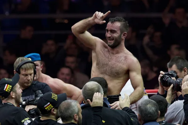 بطل الملاكمة الثقيل Agit Kabayel يحتفل بفوزه بلقب WBC وسط جمهور ومصورين، مع التركيز على انتصاره التاريخي كأول بطل ألماني منذ 1932.