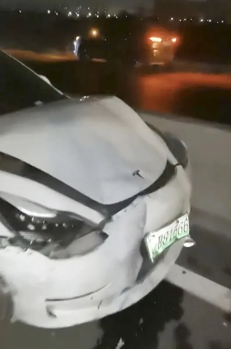تظهر الصورة سيارة تسلا موديل 3 متضررة من حادث، مع تفاصيل عن الأضرار في الجزء الخلفي. الحادث مرتبط بشكوى عن فشل المكابح.