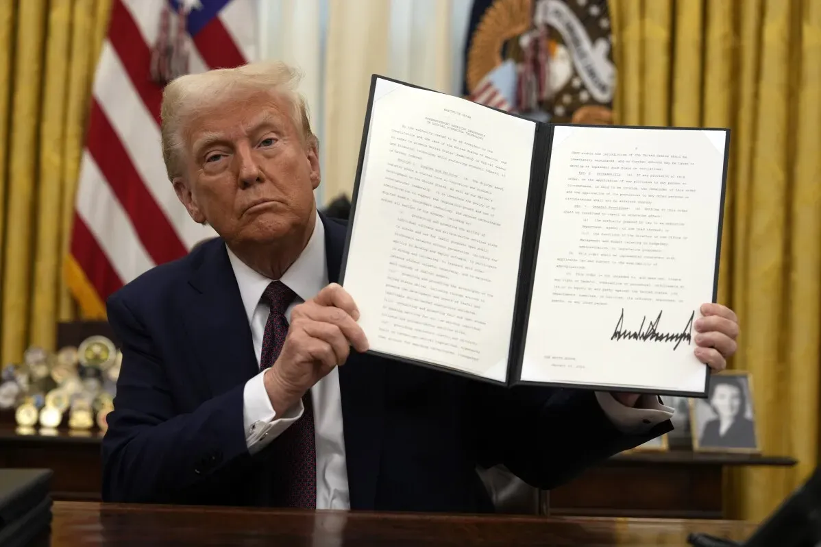 الرئيس دونالد ترامب يحمل وثيقة تنفيذية جديدة في المكتب البيضاوي، مع العلم الأمريكي خلفه، بعد أدائه اليمين في ولايته الثانية.