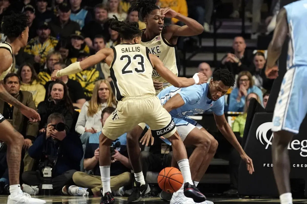 شجار حاد في مباراة كرة السلة بين فريق ويك فورست وفريق نورث كارولينا، مع التركيز على لاعب يحمل الكرة وتداخل اللاعبين في الخلفية.