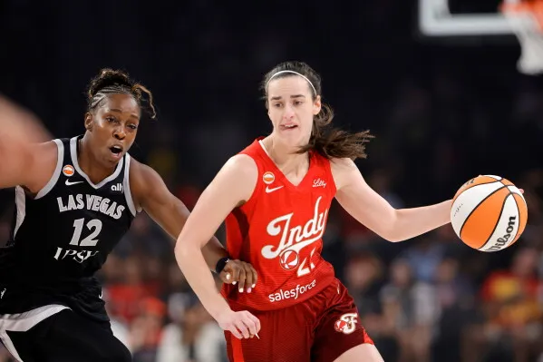 لاعبة كرة سلة من فريق Indiana Fever تحمل الكرة وتتفادى دفاع لاعبة فريق Las Vegas Aces خلال مباراة WNBA.
