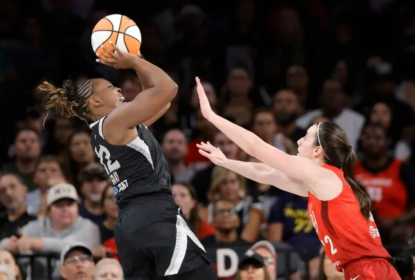 لاعبة كرة سلة من فريق Las Vegas Aces تسدد الكرة بينما تحاول لاعبة من فريق منافس صدها خلال مباراة WNBA.