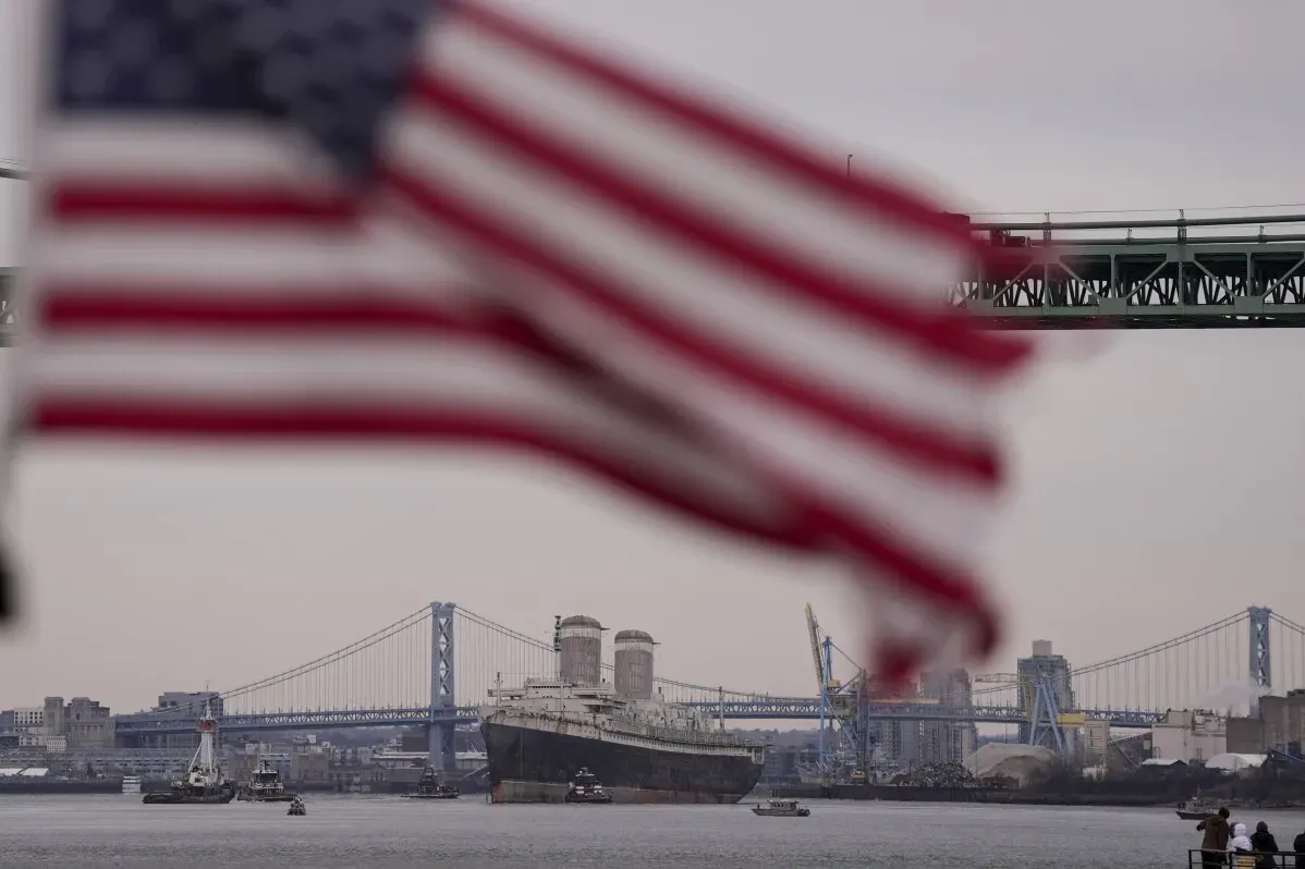 سفينة SS United States التاريخية تبحر نحو موبيل، ألاباما، لتحويلها إلى شعاب مرجانية اصطناعية، مع العلم الأمريكي في المقدمة.