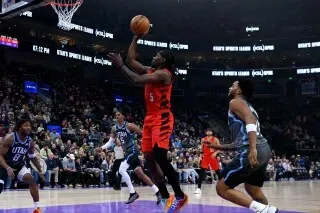 لاعب كرة سلة يسجل نقطة خلال مباراة بين بورتلاند تريل بليزرز ويوتا، مع تواجد لاعبين آخرين في الخلفية.