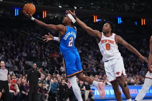 شاي جيلجوس-أليكساندر يسجل كرة سلة بينما يحاول مدافع نيويورك نيكس إعاقة تسديدته، في مباراة مثيرة بالدوري الأمريكي للمحترفين.