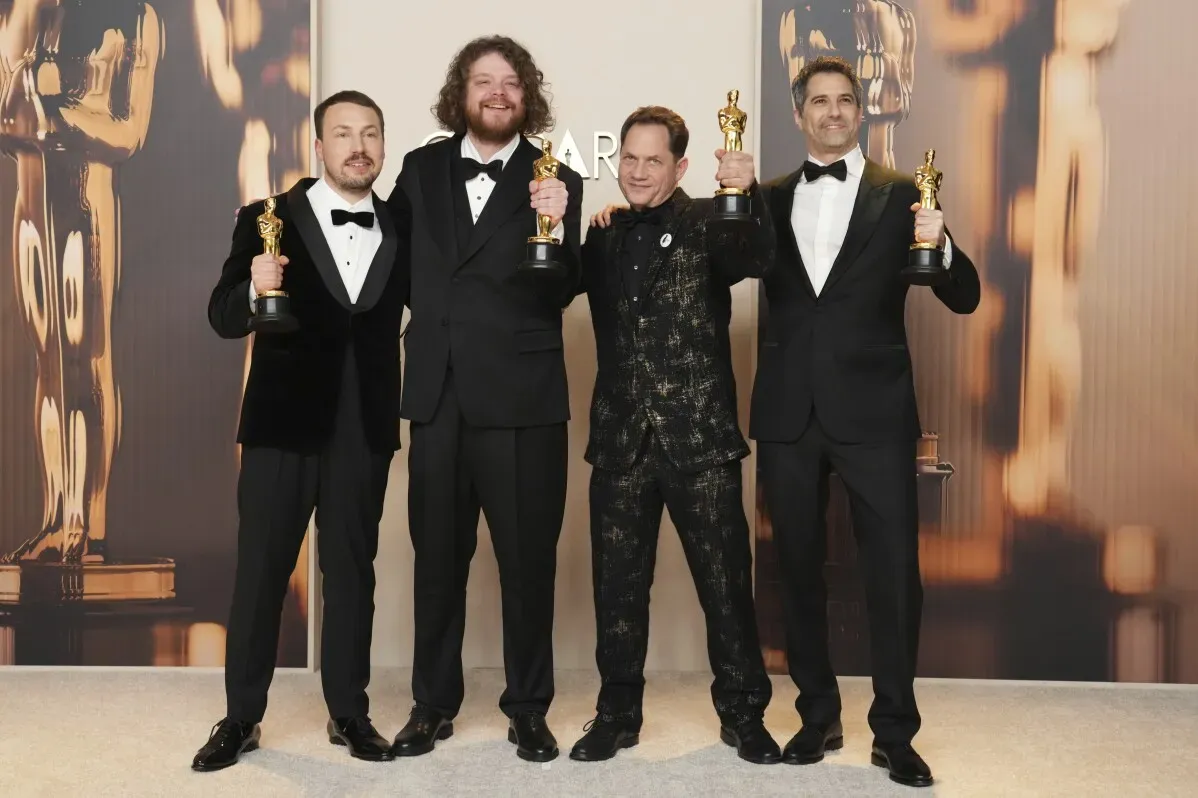 فريق فيلم "فلو" اللاتفي يحتفل بجائزة الأوسكار لأفضل فيلم رسوم متحركة، مع تماثيل الأوسكار في حفل توزيع الجوائز.