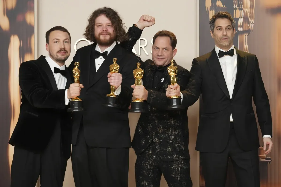 فريق عمل فيلم "فلو" اللاتفي يحتفل بجوائز الأوسكار في حفل توزيع الجوائز، مع عرض تمثال الأوسكار في أيديهم.
