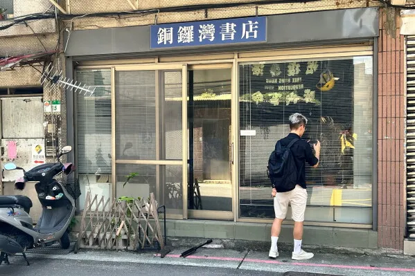 شاب يقف أمام مكتبة Causeway Bay Books المغلقة في تايبيه، رمز مقاومة حرية التعبير في هونغ كونغ بعد إغلاقها بسبب ضغوط سياسية.