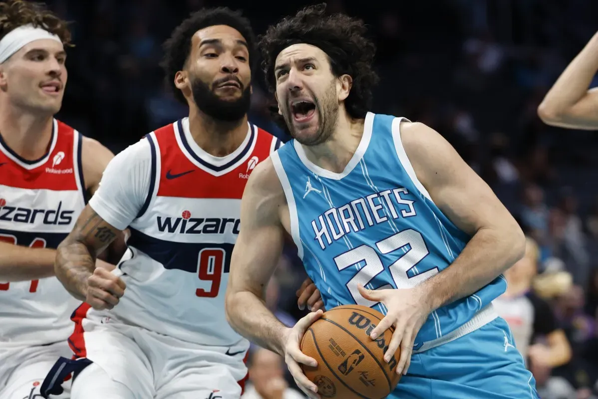 يوسف نوركيتش لاعب وسط فريق تشارلوت هورنتس يتقدم بالكرة خلال مباراة، مع وجود لاعب من فريق ويزاردز يلاحقه.