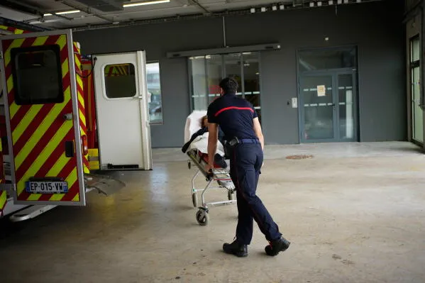 مسعف يدفع نقالة طوارئ تحمل مريضاً نحو سيارة إسعاف في مستشفى باريس-Saclay خلال موجة حر شديدة تؤثر على خدمات الطوارئ.