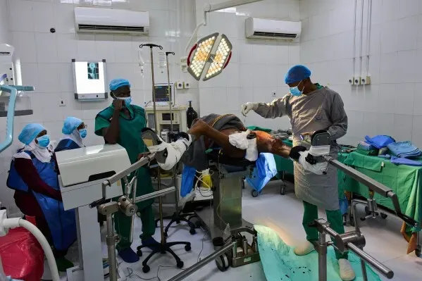 غرفة عمليات في مستشفى النهضة بأم درمان، حيث يقوم الجراح الدكتور جمال الطيب بإجراء عملية جراحية على مريض، وسط فريق طبي يرتدي معدات الوقاية.