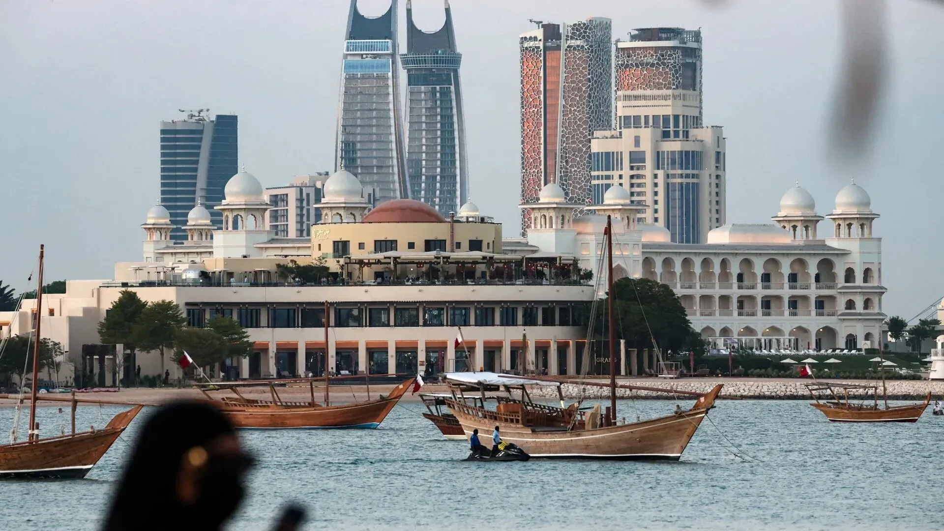 صورة تظهر مشهدًا حضريًا في الخليج، مع مباني حديثة ومراكب تقليدية، تعكس تطور موانئ المنطقة وأهميتها الاقتصادية.