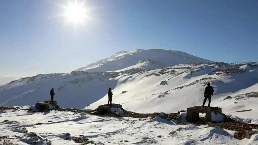 جنود إسرائيليون يقفون على مرتفعات الجولان المغطاة بالثلوج، مع جبل الشيخ في الخلفية، في سياق التوترات الإقليمية المستمرة.